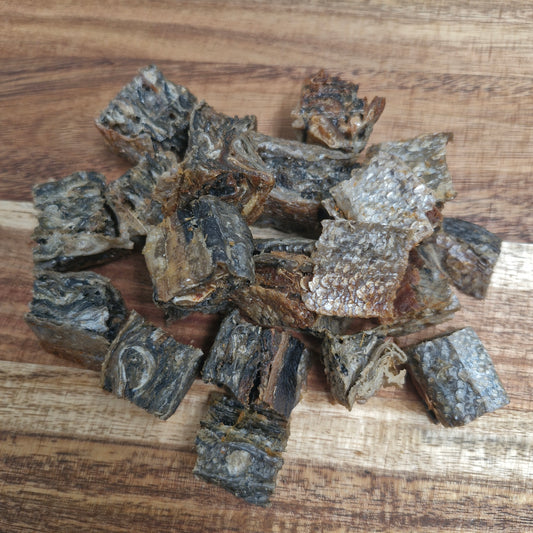 Anco Oceans salmon skin cubes natural dog treats in a pile on a wooden surface